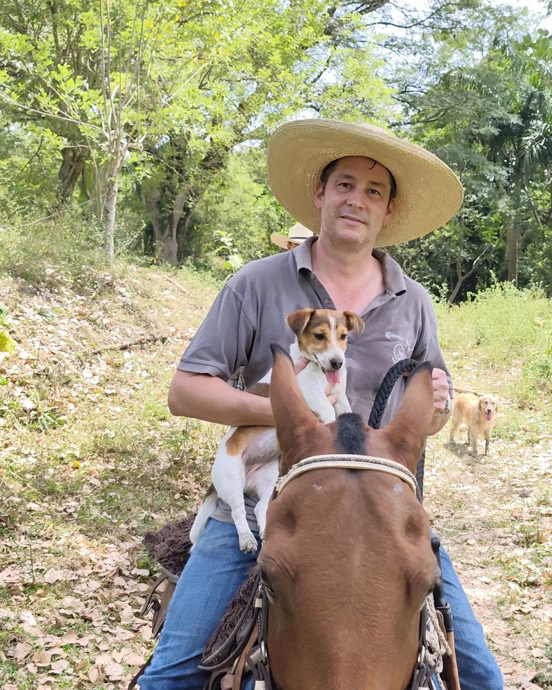Cristian Halaby a caballo con un cachorro en brazos, en un camino de la finca